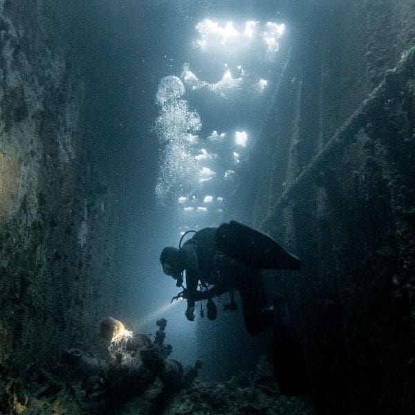 Technical diver exploring a vibrant coral reef on a liveaboard dive trip.
