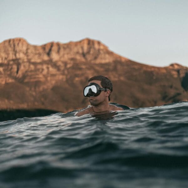 Man snorkeling in water with mountain background.
