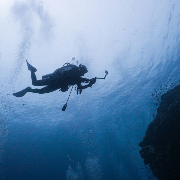 Scuba diver exploring underwater near rocky reef.