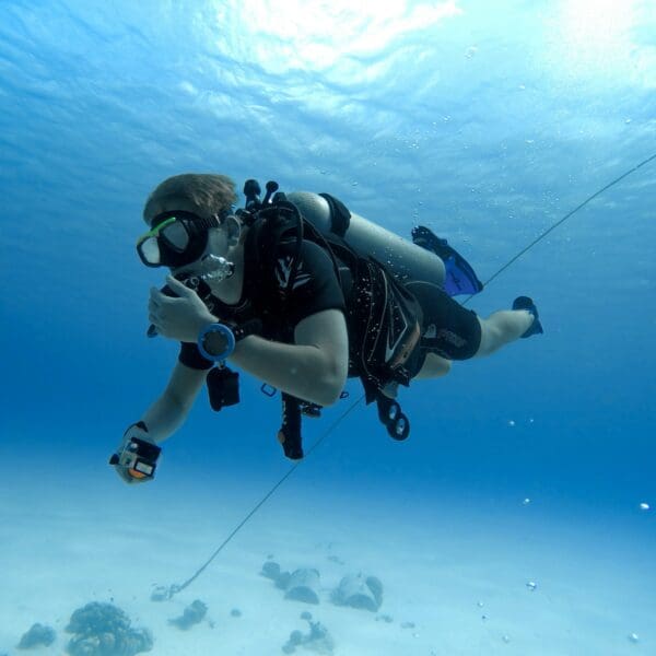 Scuba diver exploring underwater with camera in clear ocean.