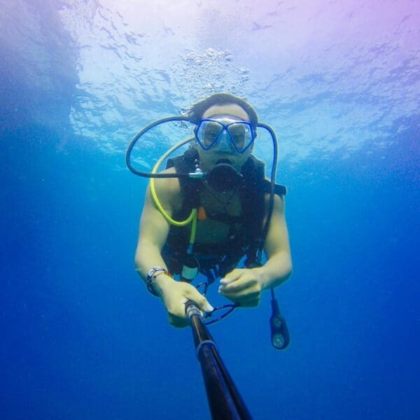 Diver with camera underwater in clear blue ocean.