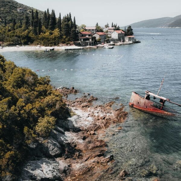 Sunken ship near coastal village with lush greenery
