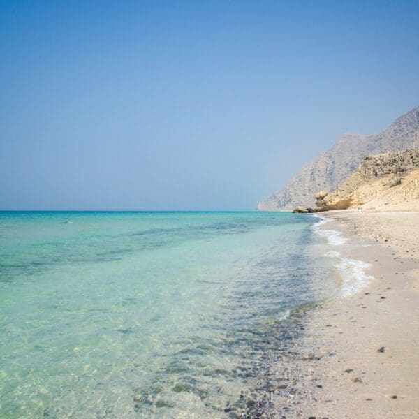 Serene beach with clear turquoise water and mountain backdrop