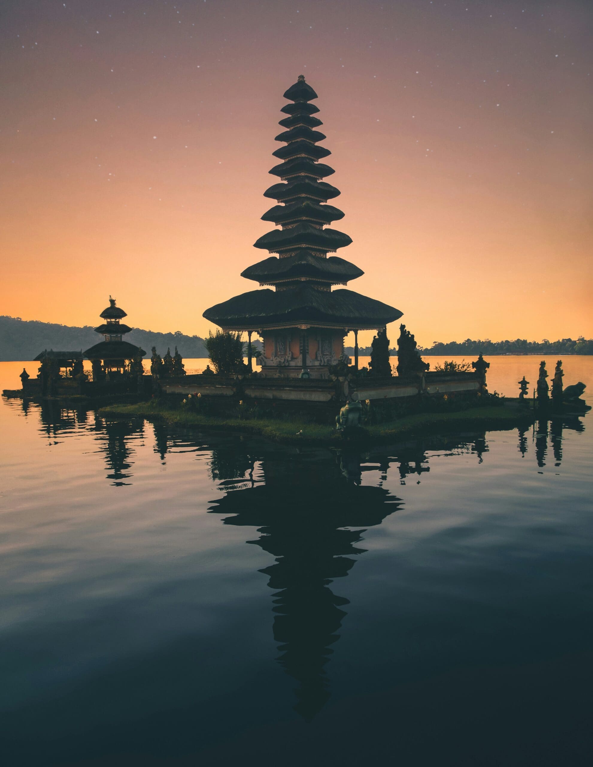 Silhouette of tiered temple at sunset by tranquil lake