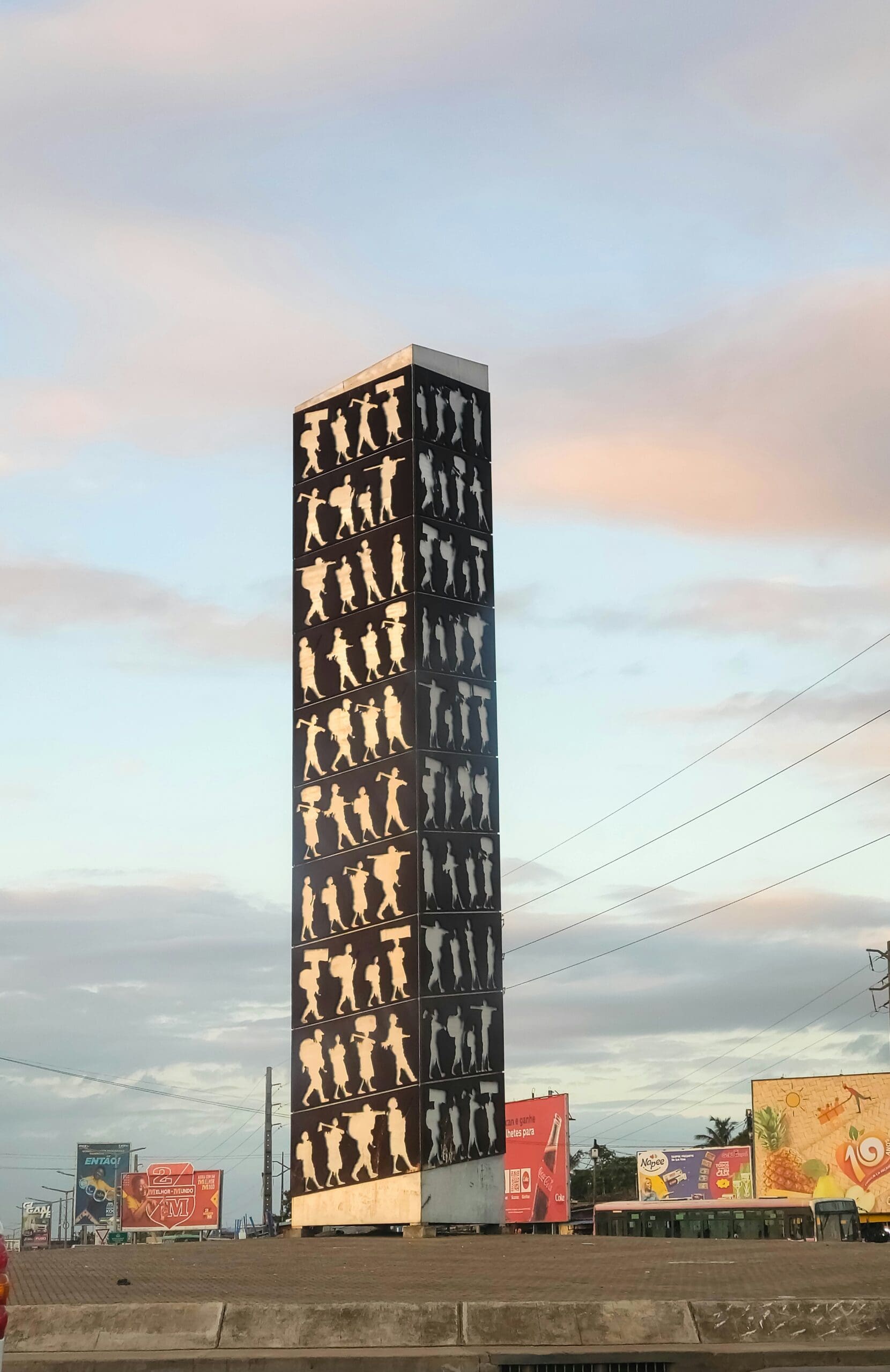Tall tower decorated with silhouetted human figures at dusk