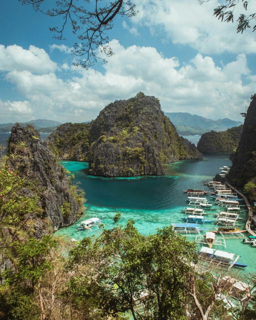 Tropical lagoon surrounded by rocky cliffs and tourist boats.