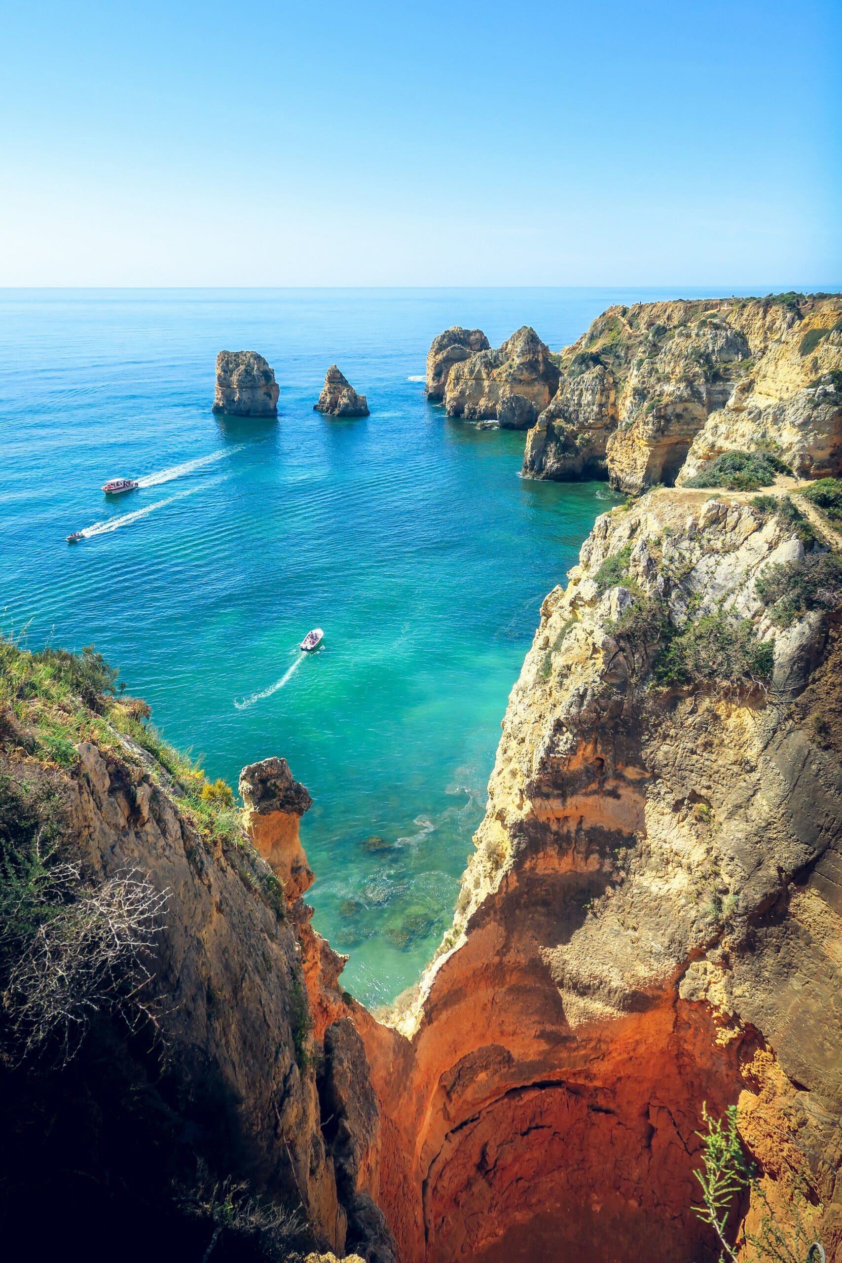 Boats sailing near rocky cliffs and clear blue water
