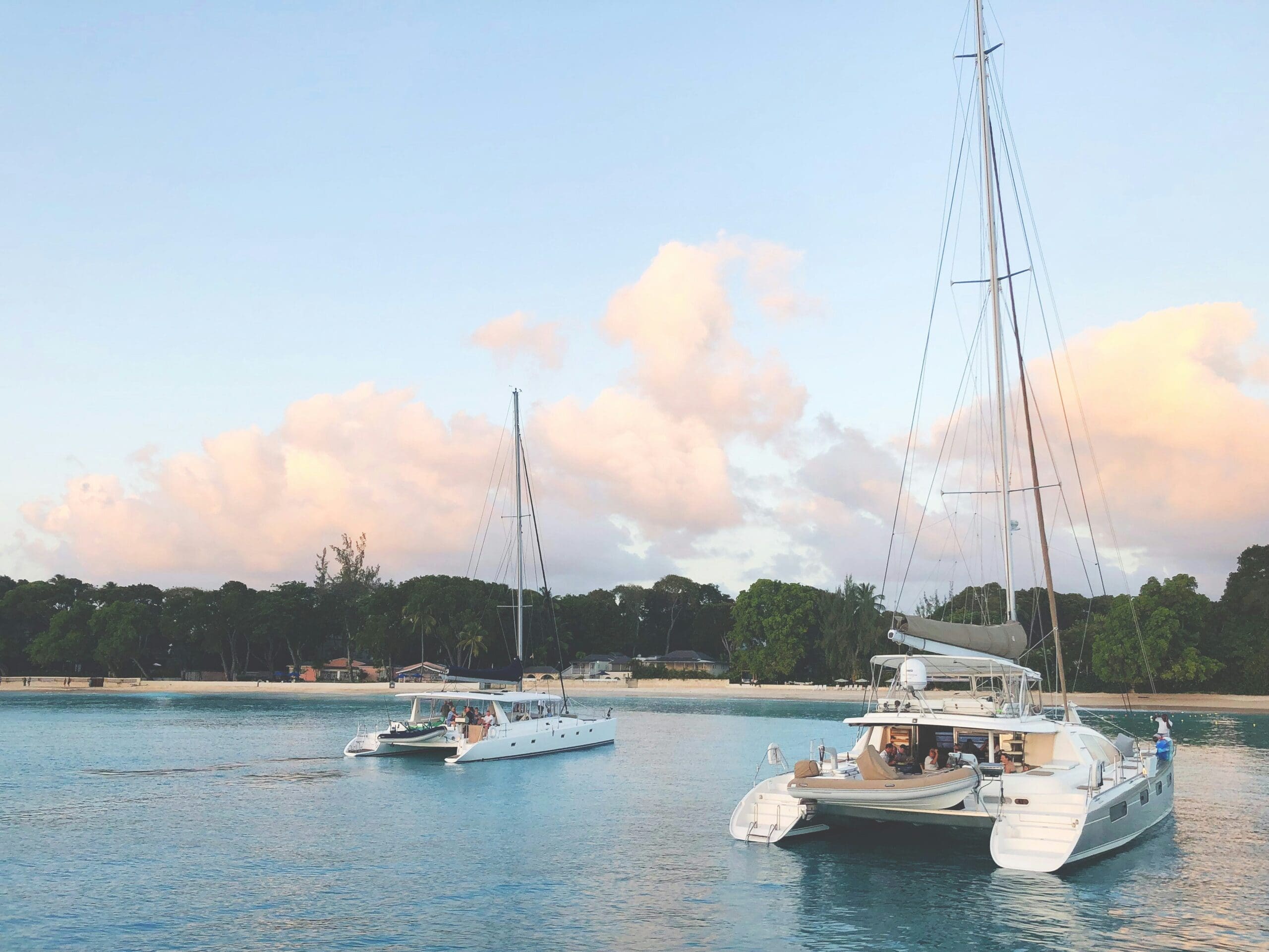 Yachts sailing near a tranquil beach at sunset