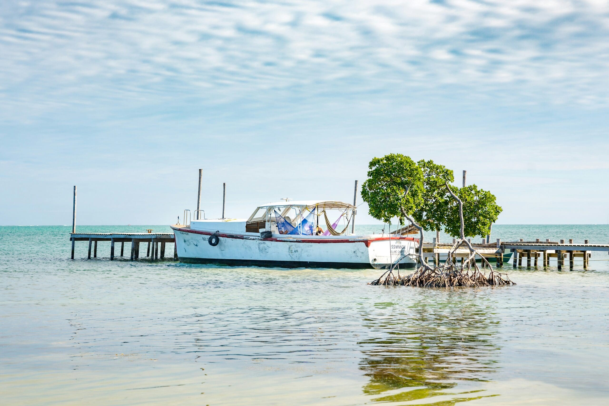 Old boat near mangroves by pier in calm sea