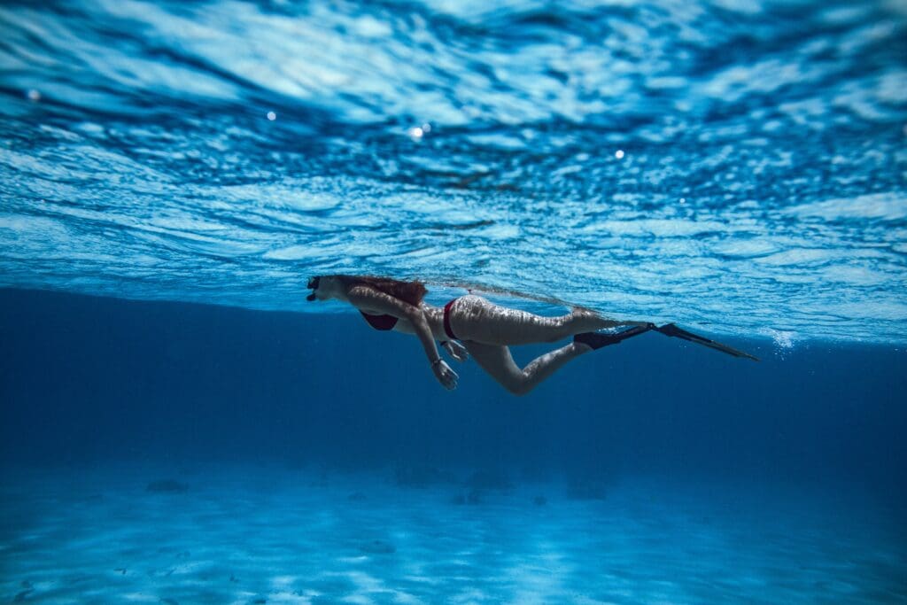 Woman swimming underwater in clear blue ocean