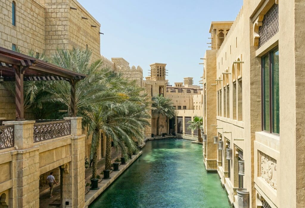 Traditional architecture along serene water canal with palm trees