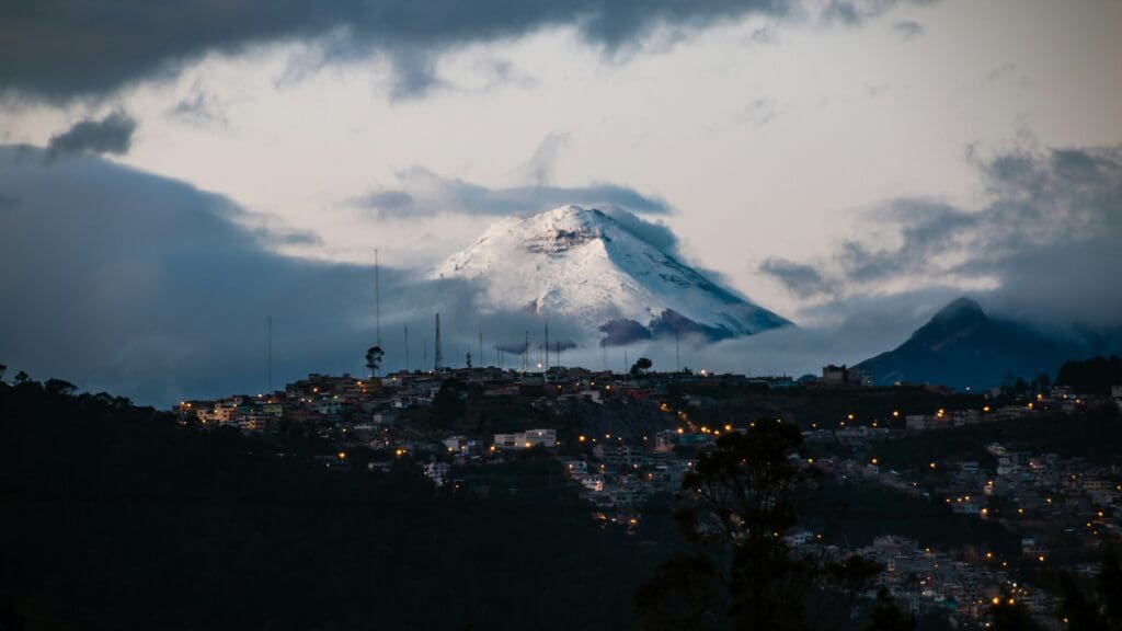 Snow-capped mountain towering over city at dusk