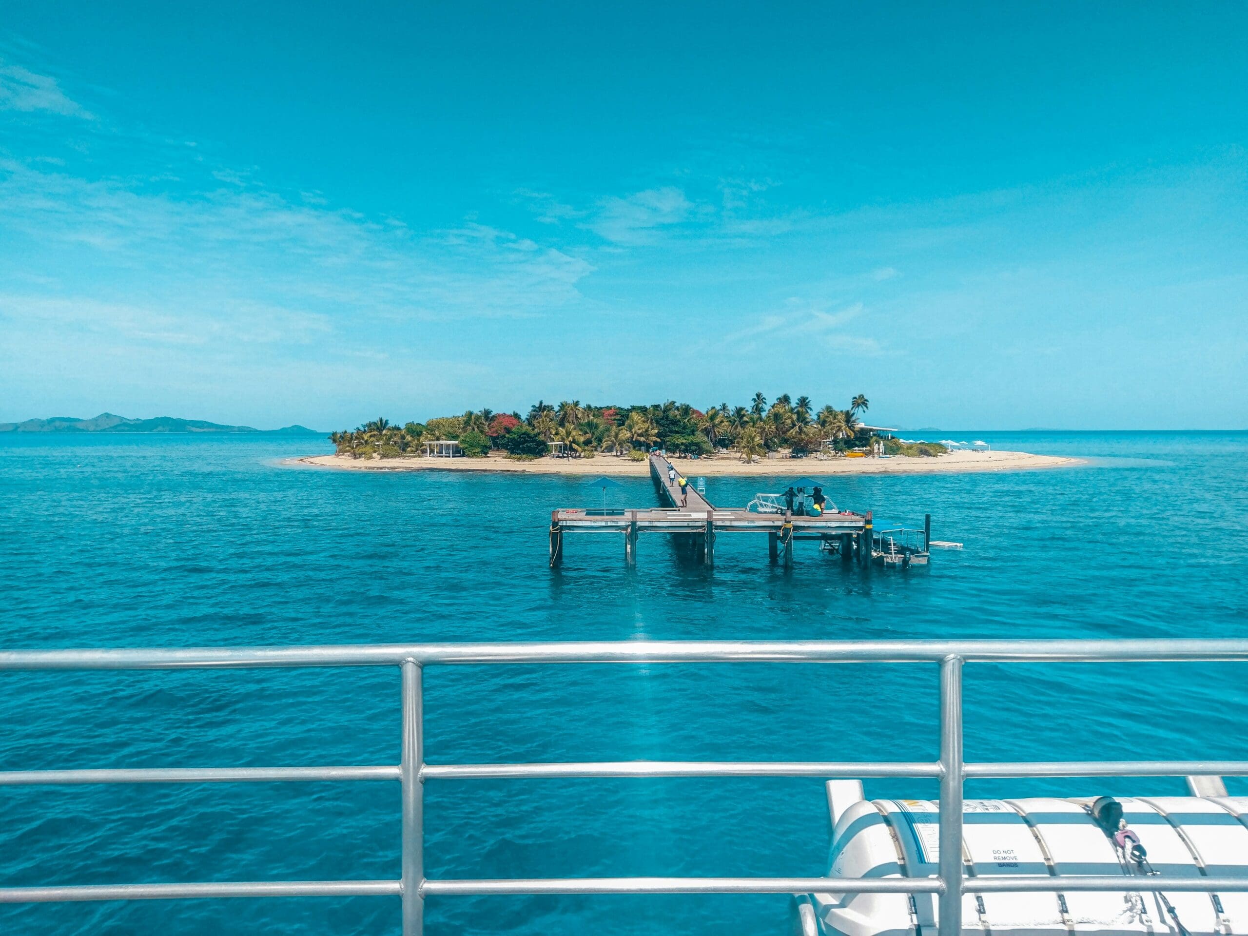 Tropical island with pier viewed from boat railing