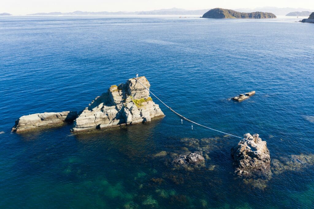 Aerial view of person tightrope walking between sea rocks