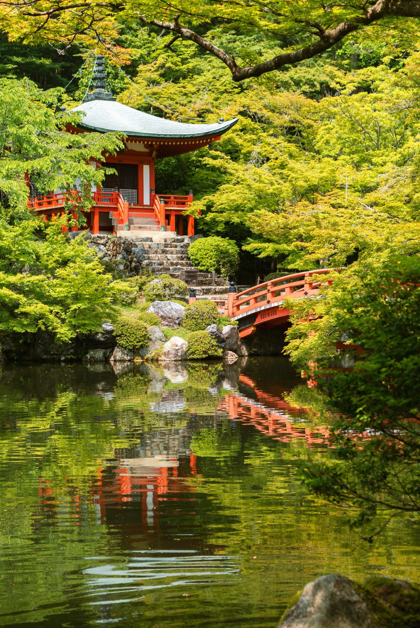Japanese temple with red bridge reflected in pond