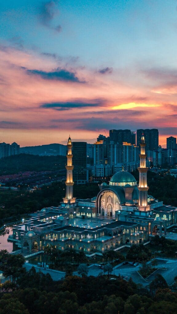 Illuminated mosque at dusk with city skyline