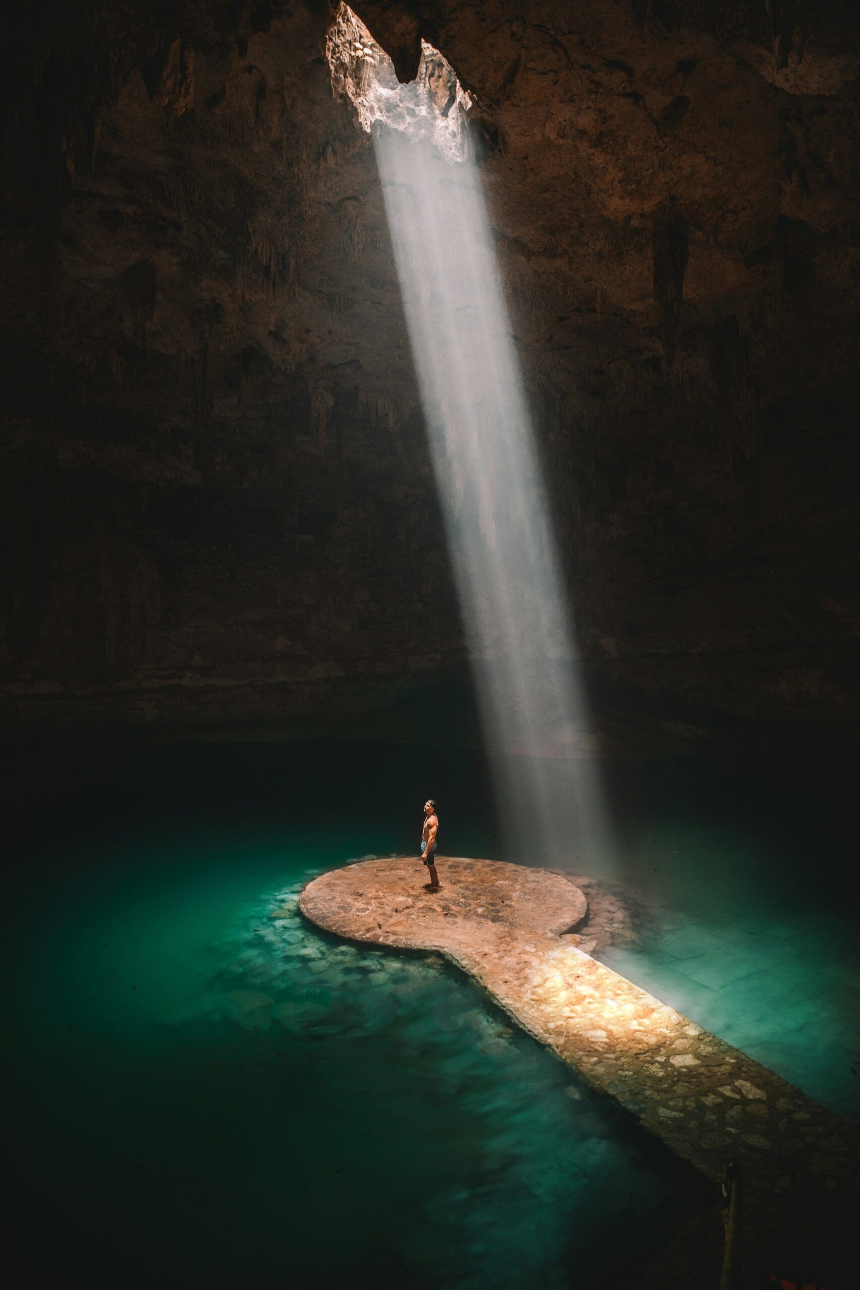 Person on rock in sunlit underground cenote