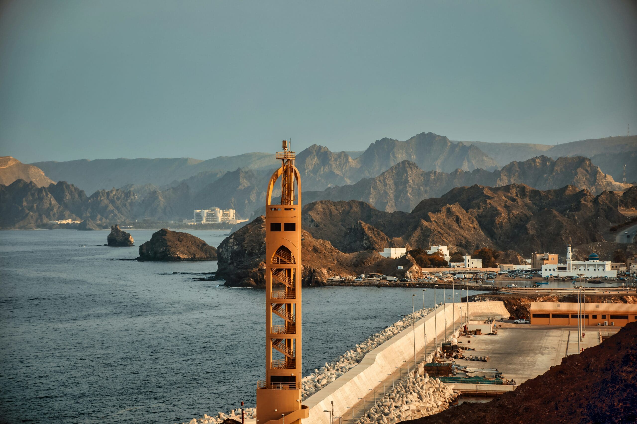 Coastal town with lighthouse overlooking rugged mountains