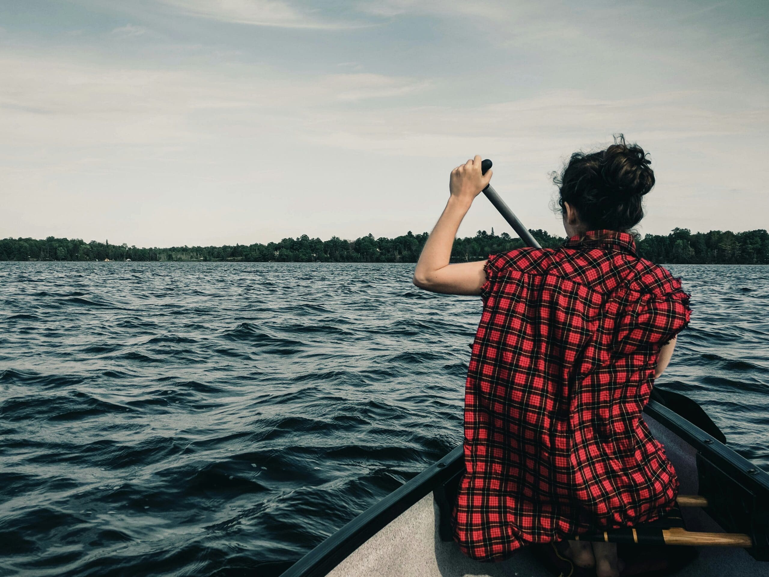 Woman paddling canoe on serene lake