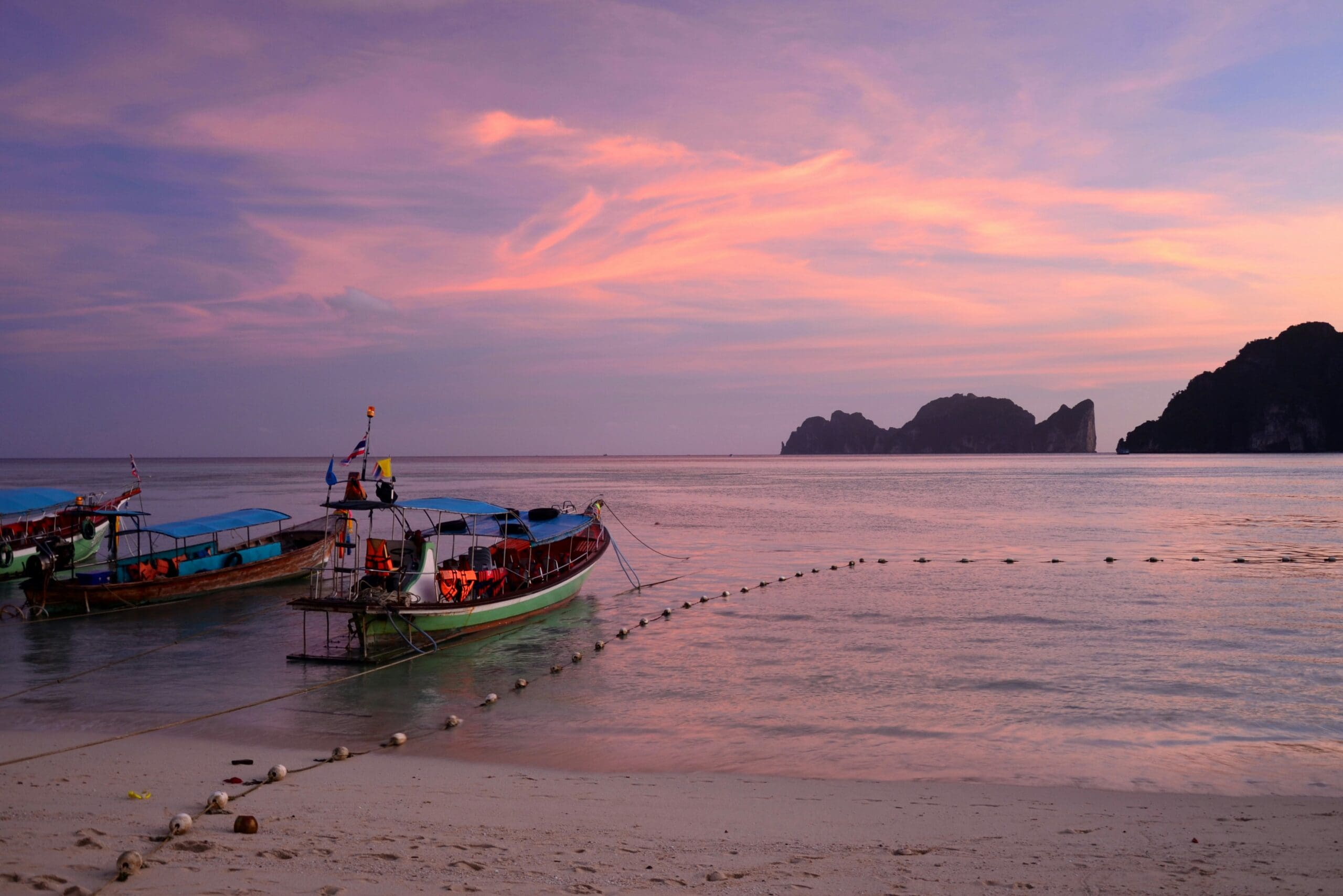 Colorful sunset over beach with moored boats