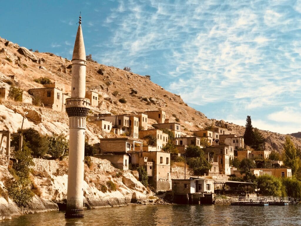 Old village and minaret by a river under blue sky