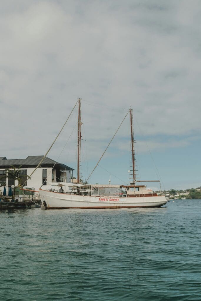 Sailing boat labeled 'Sunset Cruise' near coastal buildings