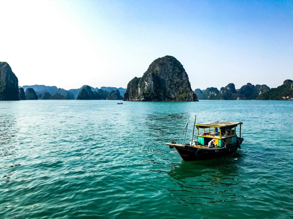 Boat floating on blue water near limestone cliffs