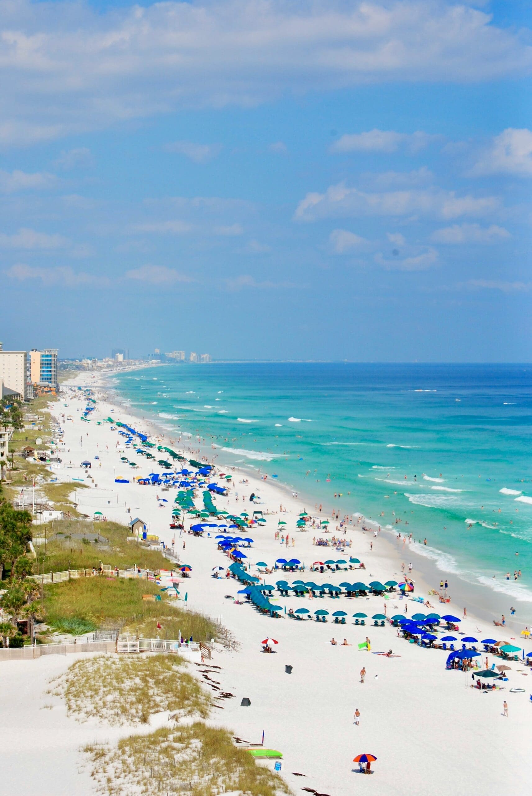 Crowded beach with blue umbrellas and turquoise water
