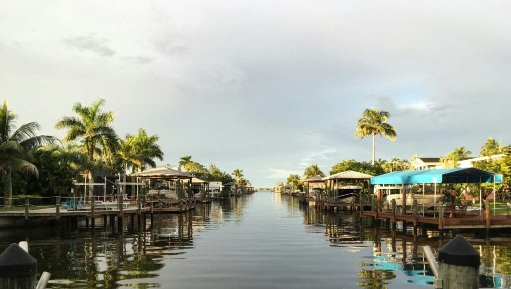 Scenic canal with boats and palm trees at sunset