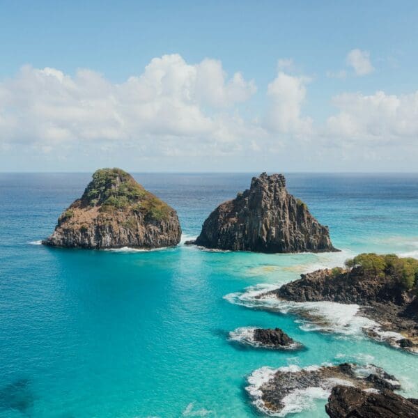 brown and green rock formation on blue sea under white clouds and blue sky during daytime